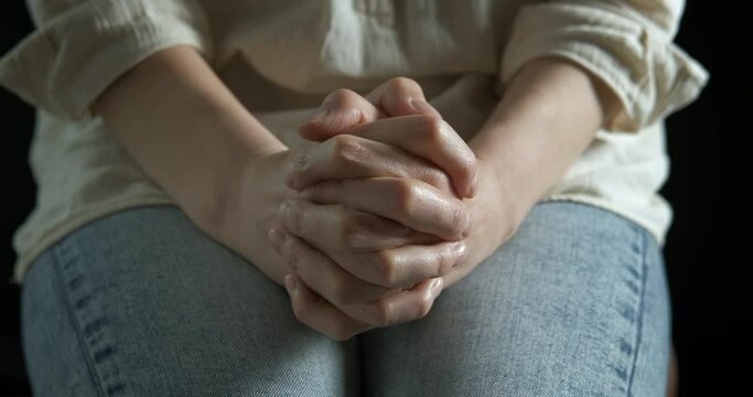 Praying mood in the dark. A view of stressed female hands in the dark room.