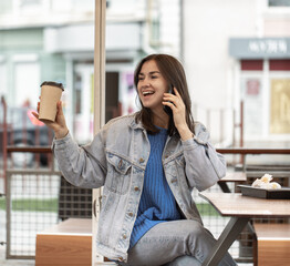 Street portrait of a cheerful young woman talking on the phone.