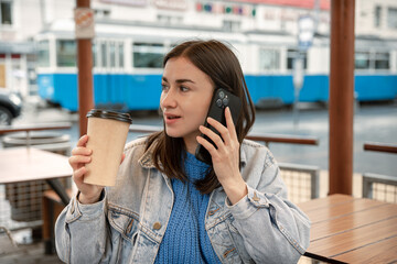 Young woman is drinking coffee and talking on the phone.