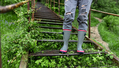 Close-up of a girl in rubber boots on a walk in the spring forest.