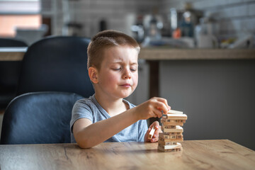 Serious little boy playing board game with wooden turret.
