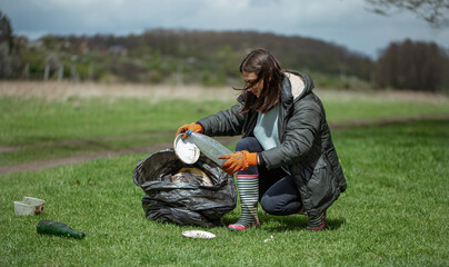 Volunteer girl cleans the forest from plastic and other debris.