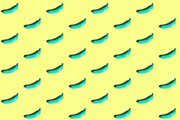 Minimal repetitive patter made of blue bananas on yellow background.