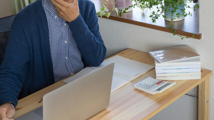 自宅で勉強をする男性。考え込む男性。