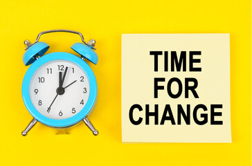 On a yellow background lie a clock and a sticker sheet with the inscription - TIME FOR CHANGE