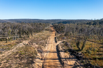 Drone aerial photograph of telephone wires along a dirt track in a forest