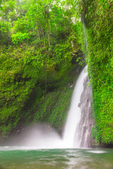 a view of a slow motion waterfall with green walls in a tropical forest