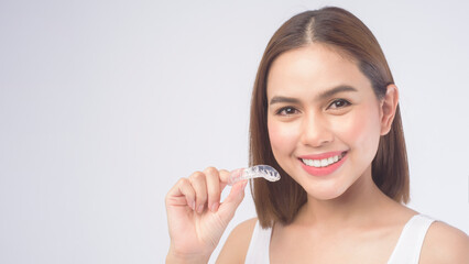 Young smiling woman holding invisalign braces over white background studio, dental healthcare and Orthodontic concept.