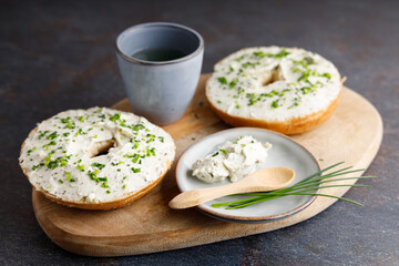 Breakfast table with bagels fresh cheese. Bagels with fresh cheese and herbs on a breakfast table , with fresh orange juice and coffee on the side.