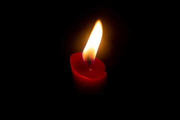 Red candle with yellow flame on black background