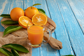 Fresh orange and a glass of orange juice on a wooden table background