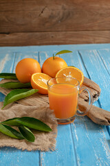 Fresh orange and a glass of orange juice on a wooden table background