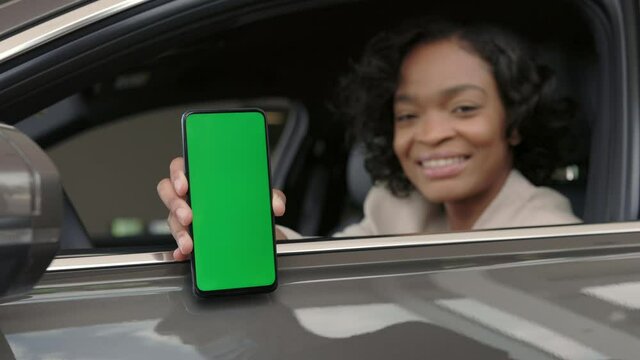 Arican woman sitting in auto with green sreen on mobile