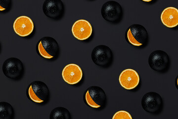 The pattern of black painted oranges cut onto round slices on black background. Creative food concept. Summer citrus fruit isolated on a black background. Flat lay, top view.