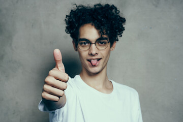 Cheerful cute guy with curly hair shows thumb up emotions