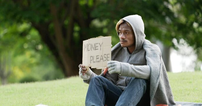 Homeless man sitting and holding money please sign