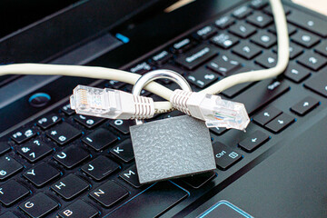 internet cable passing through a closed iron lock on a laptop keyboard data protection concept...