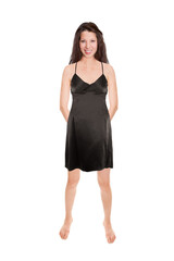 Happy young woman wearing an elegant black evening dress with her hands on her back, isolated in front of white studio background