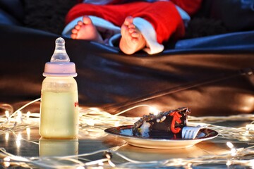 Baby sleeping after Christmas celebrations. Milk bottles and cakes are also seen in the photo. High quality photo