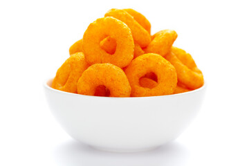 Popular Ready to eat crunchy and puffed snacks ring tangy orange color in a white ceramic bowl. Top view, Side lit,