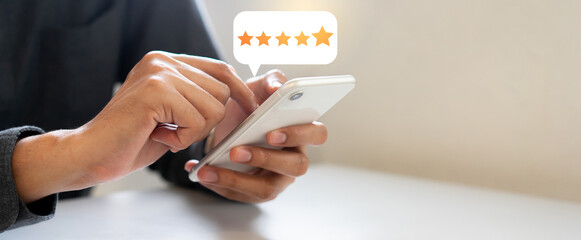 close up on man hand press on smartphone screen with gold five star rating feedback icon and press...
