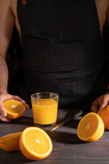 a man in a dark apron crushes orange juice