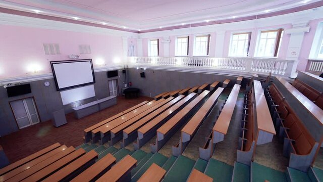 Contemporary auditorium for students. White board in the large classroom in front of wooden desks in the university.