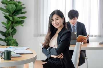 Charming businesswoman crossed arms on an office sit chair with a blur back looking at the camera.