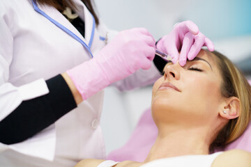 Doctor performing rhinoplasty by injection of hyaluronic acid in the nose of his patient.