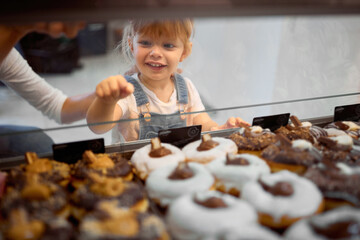 Portrait of a toddler girl picking up tasty donuts