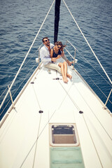 A young couple in love is sitting in a hug on the bow of the yacht and spending wonderful time together on the sea. Summer, sea, vacation, relationship