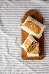 Homemade Breakfast Egg Burrito with Avocado and Bacon on a rustic wooden board, top view. Flat lay, overhead, from above. Space for text.