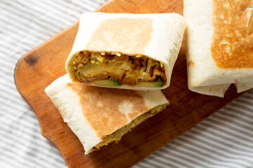 Homemade Breakfast Egg Burrito with Avocado and Bacon on a rustic wooden board, top view. Flat lay, overhead, from above. Close-up.