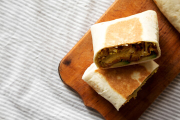 Homemade Breakfast Egg Burrito with Avocado and Bacon on a rustic wooden board, top view. Flat lay, overhead, from above.