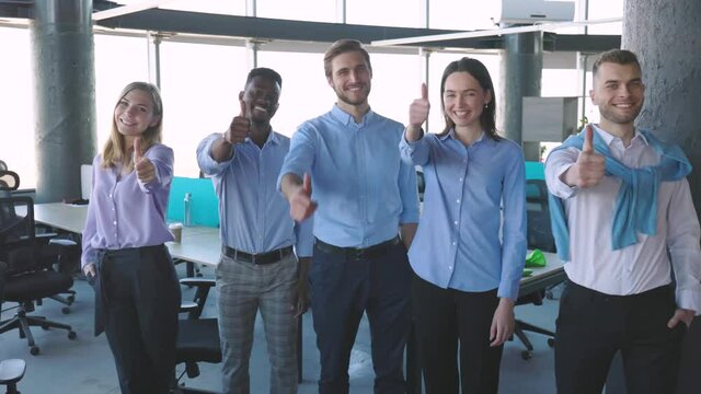 Happy businesspeople standing in office showing thumb up.