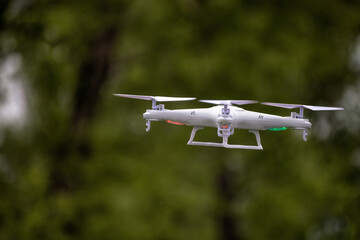 A white drone quadcopter taking off from the ground. Soft focus. Motion blur.