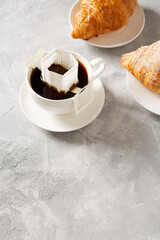 Cup of coffee with drip filter and croissant