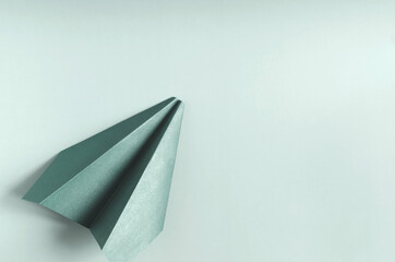 Concept paper airplane in green color on a green background of kopi space. Origami bright green paper airplane