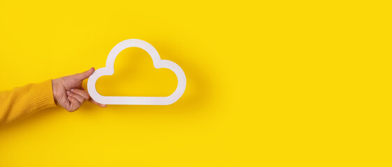 hand holding cloud icon over yellow background, panoramic mock-up