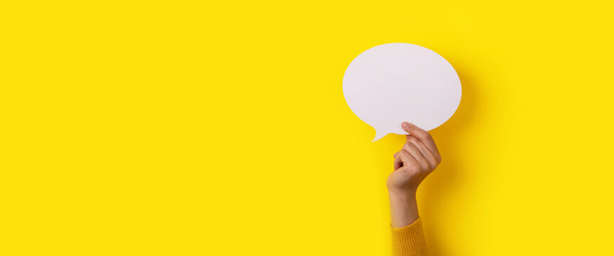 bubble speech layout in hand over yellow background, panoramic mock-up
