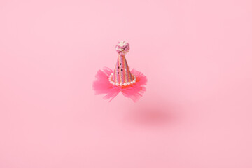 kids cone party hat levitation in air over pink background, festive mood and birthday concept