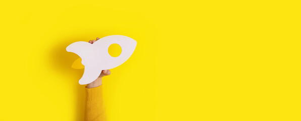 rocket in hand over yellow background, panoramic layout