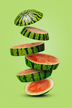 Naklejki Summer fruit arrangement with slices of watermelon falling down stacked on a light green background. Creative food concept.