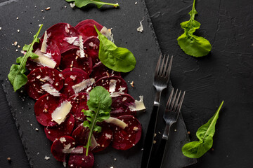 Young beet carpaccio with parmesan, nuts, arugula and garlic with olive oil. Vegan food.