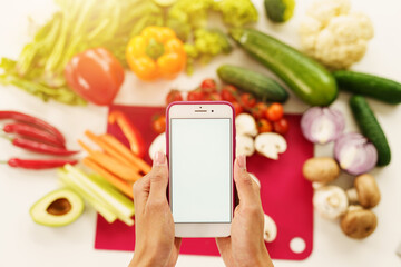 Cook follows a recipe of vegetables from the smartphone - obrazy, fototapety, plakaty