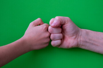 two hands bumping fists on a green background