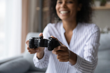 Crop close up of smiling African American woman hold gamepad controller play computer video games at home. Overjoyed millennial female gamer use joypad engaged in electronic entertainment app.