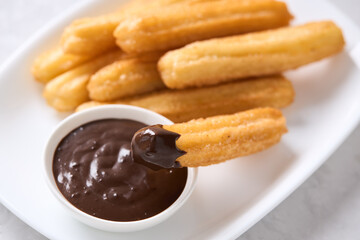 Churros with sugar and chocolate on a light background. Traditional Spanish fast food, homemade baking.