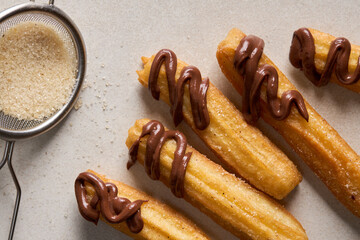 Churros with sugar and chocolate on a light background. Traditional Spanish fast food, homemade baking.