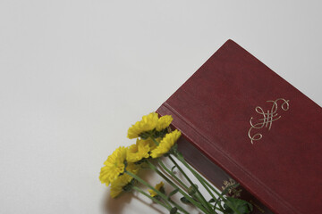 An old book and yellow flowers in the composition with no title. Ornament or monogram and free...
